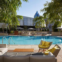 A tranquil hotel poolside setting with loungers and a yellow accent chair